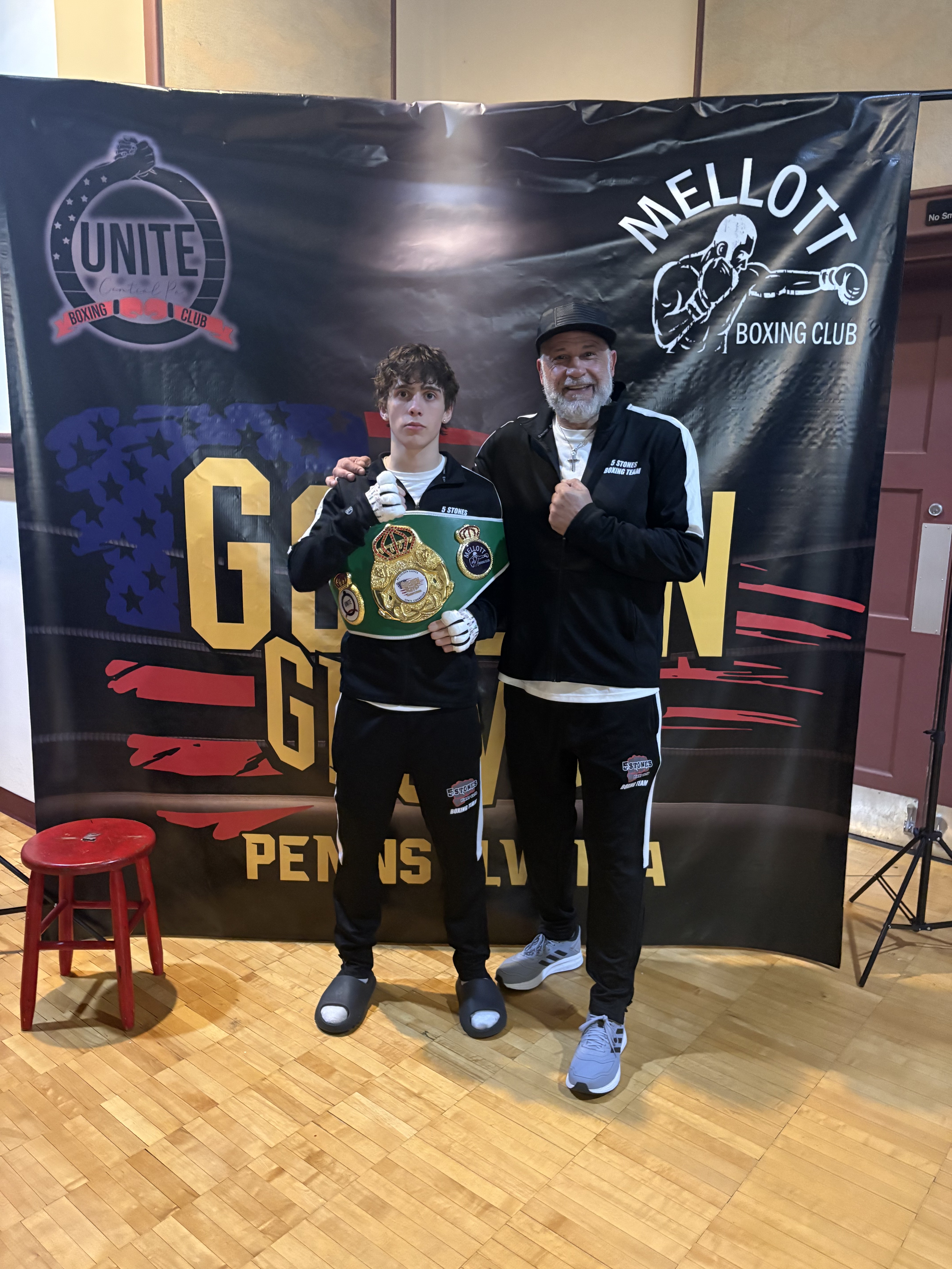 Andrew Waybright holding his championship belt beside his Five Stones coach