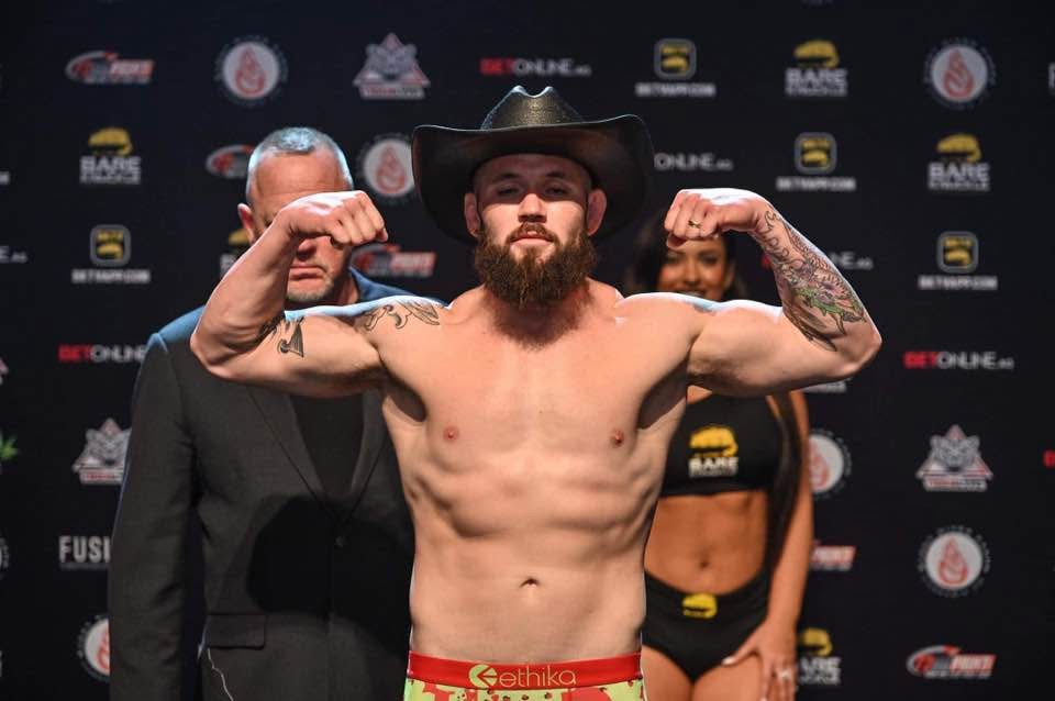 Dave "Redneck" Mundell flexing at a BKFC weigh-in in a black cowboy hat